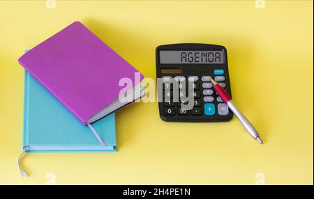 Calculator with agenda text on white background, plus colored notepads and stickers Stock Photo