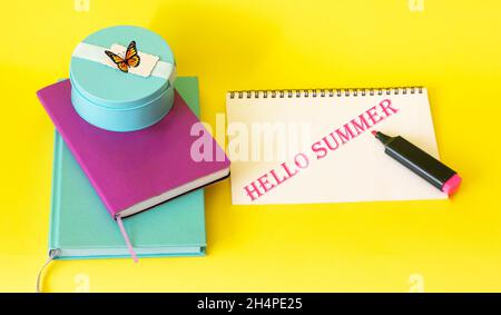 On a yellow background colorful notebooks, felt-tip pen and notebook with text hello summer Stock Photo