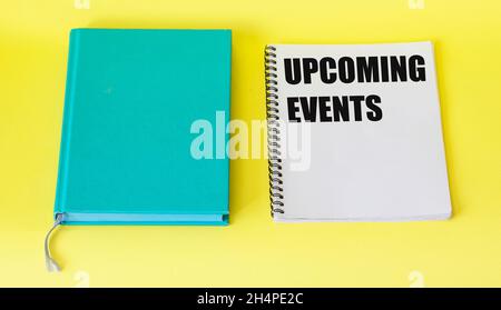 Message upcoming events concept on notebook with pen and notepad on yellow table Stock Photo