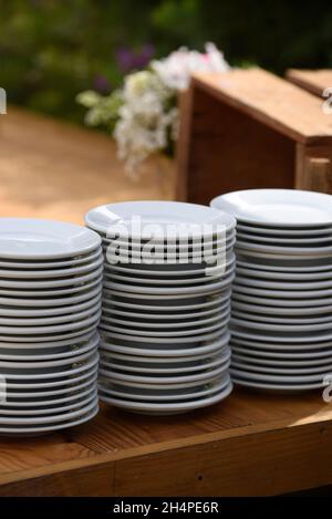 A stack of clean white dishes on a wooden table. Stock Photo