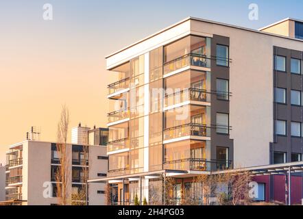 Modern luxury apartment building, block of flats with glass balconies in the sunset light. Real estate. Cozy evening ambiance in residential area Stock Photo