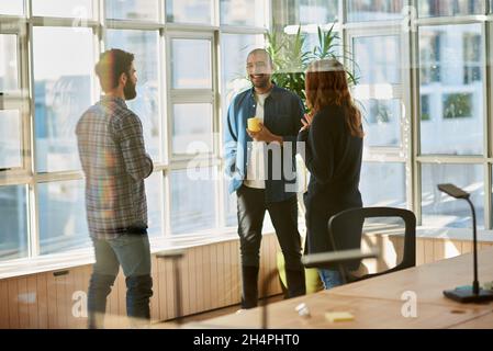 Laughing group of young businesspeople talking inside an office Stock Photo