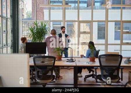 Young businessman talking with colleagues over coffee in an office Stock Photo