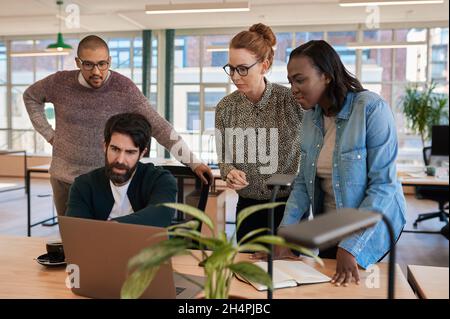 Focused group of diverse businesspeople working on a laptop together Stock Photo