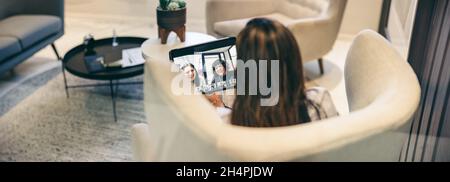 Anonymous businesswoman attending a video conference in an office. Rearview of a businesswoman using a digital tablet for a virtual meeting with her p Stock Photo