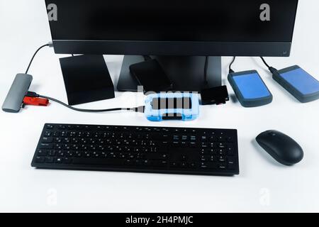 Multiple external hard drives connected to a monoblock on a white background.Computer with hard drive. Stock Photo