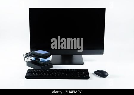Multiple external hard drives connected to a monoblock on a white background.Computer with hard drive. Stock Photo