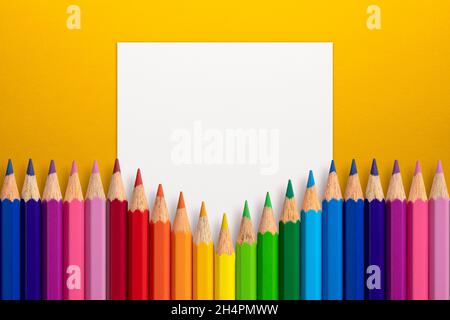 Creative layout made of color pencils on yellow paper background with white paper card note. Flat lay. Education concept. Stock Photo