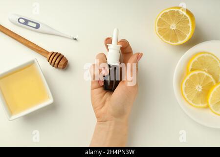 Female hand holds blank bottle of nasal spray on white background with flu treatment accessories Stock Photo