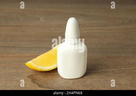 Blank bottle of nasal spray and lemon slice on wooden background Stock Photo