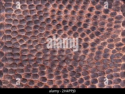Close-up of rough handmade textured wooden surface carved as snake skin pattern and painted in dark brown color with black stains. Empty multicolored Stock Photo