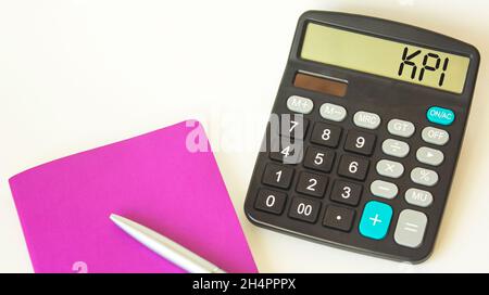KPI text on calculator, pen and notepad on white background. Goal concept. Stock Photo