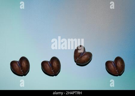 Imperfect row of four ripe brown and blue natural heart shaped plums on multicolored peach, blue and green textured paper background. Pattern with har Stock Photo
