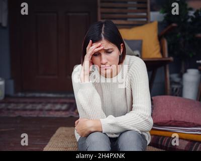 Young depressed asian woman sitting on porch of backyard. She feeling sad and worried suffering depression in mental health. Mental health, anxiety de Stock Photo