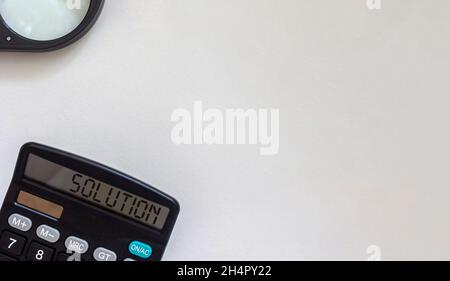 Business concept. Calculator and magnifying glass on paper white background Stock Photo