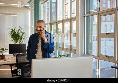 Smiling young businessman talking on his phone in an office Stock Photo