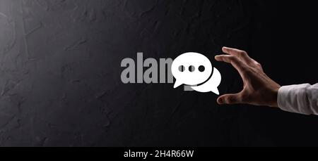 Businessman holding a message icon, bubble talk notification sign in his hands. Chat icon, sms icon, comments icon, speech bubbles. Stock Photo
