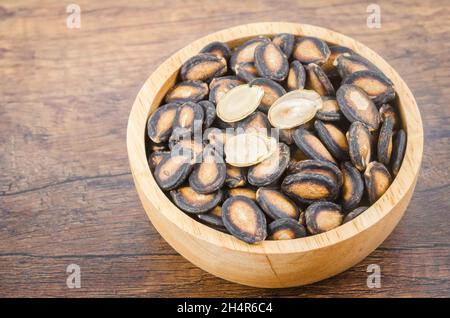 Black dry watermelon seeds in wooden bowl on the table. Stock Photo