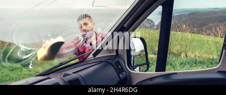 Man cleaning camper van windshield outdoor Stock Photo