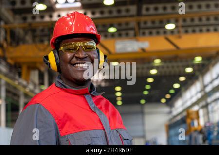 Smiling African American Worker In Personal Protective Equipment Holding Clipboard And Looking At Camera. Portrait Of Black Industrial Worker . Stock Photo