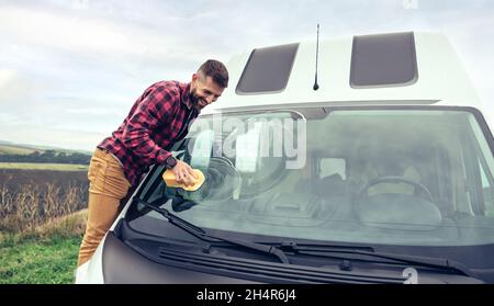 Man cleaning camper van glass outdoor Stock Photo