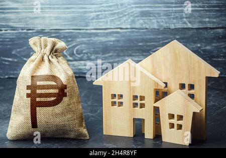 Philippine peso money bag and figurines of residential buildings. Property tax. Municipal budgeting. Increase investment attractiveness. Financing urb Stock Photo