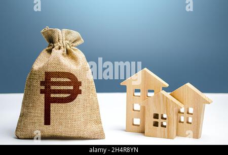 Philippine peso money bag and residential buildings. City municipal budget. Property tax. Investment in real estate. Costs of service and maintaining. Stock Photo