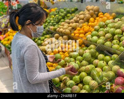 Pregnant woman buying cainito or star apple fruit at fruit store Stock Photo