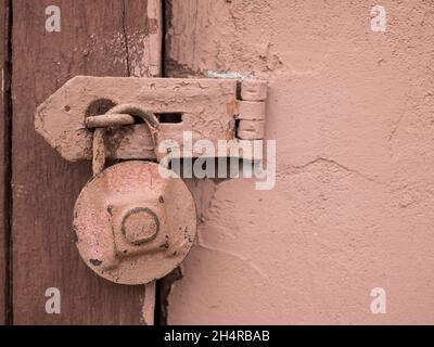 Rusty pink padlock hanging on the wooden door. Rustic, retro detachable lock, close up Stock Photo