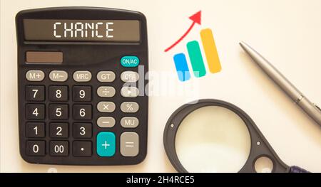 On a white background a calculator with the text chance, graph, pen and magnifier Stock Photo