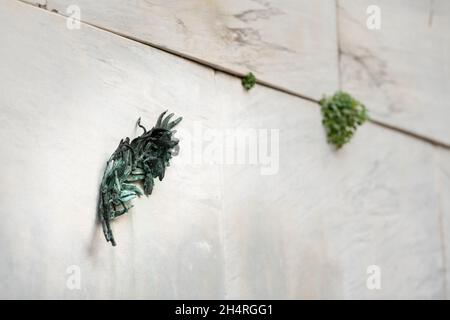 Bronze feather on a white marble wall, Venice (Italy), cloudy day in autumn Stock Photo