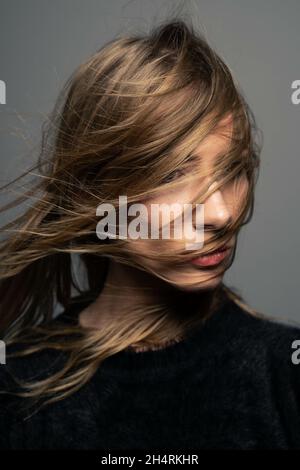Woman covering face with gray sweater in front of wall Stock Photo - Alamy