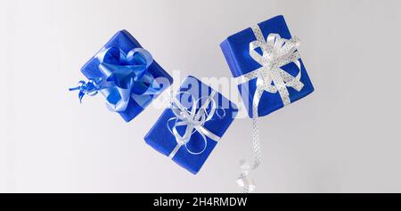 Boxing Day. Levitation of three gifts in blue paper with a white ribbon on a white background. Christmas gifts, new year empty background Stock Photo