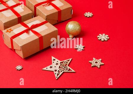 Craft boxes and decorative wooden Christmas tree toys on a red background. Christmas background. Christmas, New Year gifts made of eco-material Stock Photo