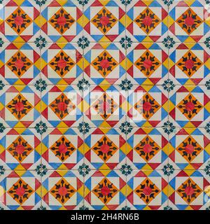 Fragment of building wall with colorful ceramic wall tiles. Azulejos close up. Abstract decorative background. Traditional Portuguese architecture. Stock Photo