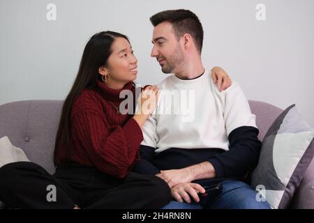 Young couple relaxing on a couch at home using laptop and smiling. Stock Photo