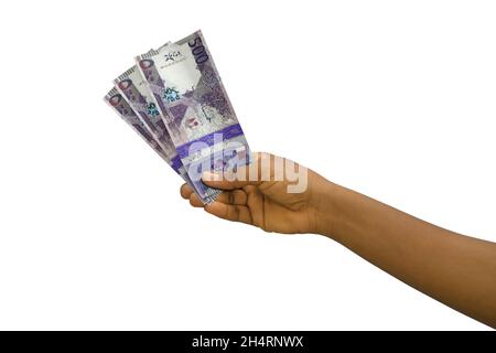 Fair hand holding 3D rendered Qatari riyal notes isolated on white background Stock Photo