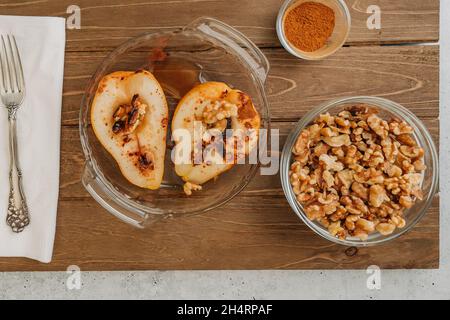 Baked pears with walnuts, honey, and cinnamon, close up o rustic background, perfect breakfast or dessert. Stock Photo