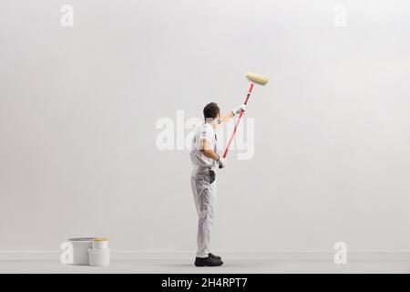 Painter using a paint roller and painting a wall isolated on white background Stock Photo