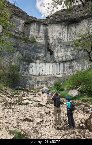Malham Cove, view in summer of people visiting Malham Cove, a 260ft cliff sited in Malhamdale, an area of outstanding natural beauty in Yorkshire, UK Stock Photo