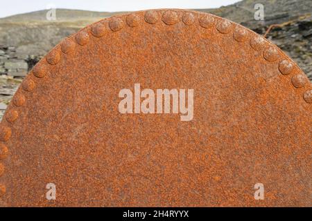 Rusty rivets on corroded metal machinery part in disused slate quarry. Stock Photo