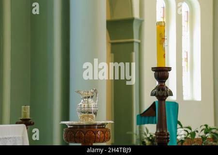 Illustrative scene of baptism in a Catholic church with baptismal font, water jug, candles and paschal candle Stock Photo