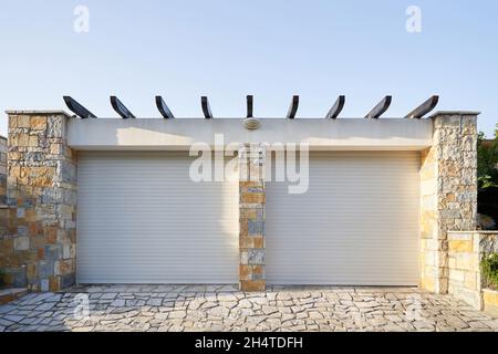 Modern private garage with white automatic rolling doors for 2 cars.exterior Stock Photo