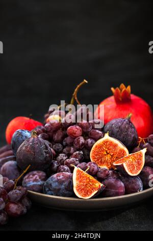 Fresh autumn fruits -  figs, plums, grapes and pomegranate on dark background Stock Photo