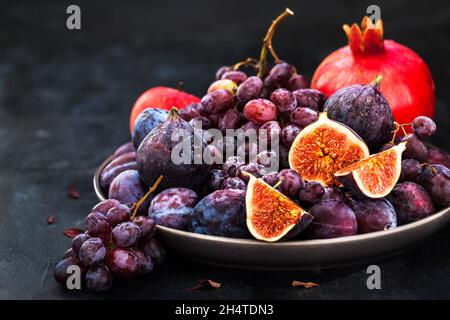 Fresh autumn fruits -  figs, plums, grapes and pomegranate on dark background Stock Photo