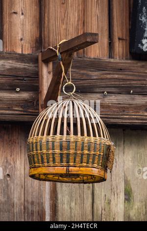 An empty wicker bird cage hanging on a street in Xingping, China. Stock Photo
