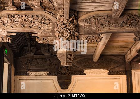 Elaborate wood carving of lotus flowers & a battle scene on the ceiling of an old building in Wuzhen, China. Stock Photo