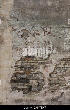 Chinese writing on the damaged plaster wall of an old building in Wuzhen, China. Stock Photo