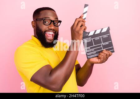 Photo of happy trendy afro american cheerful brown haired man hold hands clapper isolated on pink color background Stock Photo