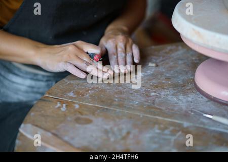 Table in pottery studio with hand of master work on handmade details for potter kitchenware decor Stock Photo